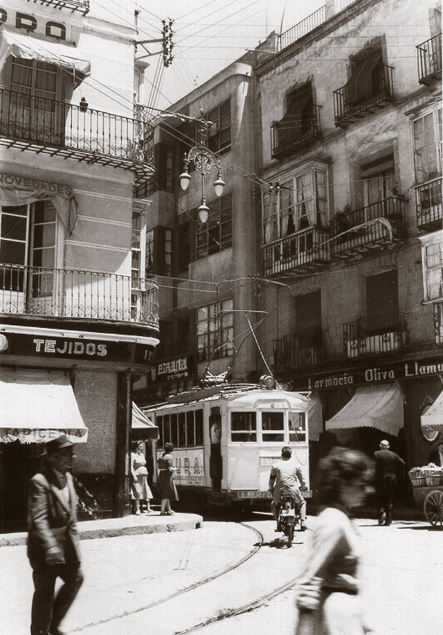 1942. La Plaza de San Ginés en los últimos años del tránsito en tranvía. En la fotografía aparece la tienda Viñas y Navarro y la farmacia de Oliva Llamusí.